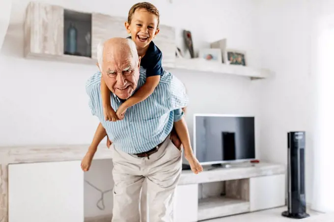 Portrait of grandfather giving his grandson a piggyback ride in the living room