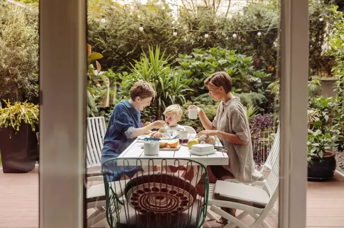 Two happy mothers at breakfast table outdoors with their child