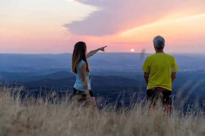 Spain, Catalonia, Montcau, senior father and adult daughter looking at view from top of hill during sunset