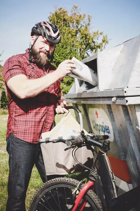 Portrait of cyclist recycling waste paper in paper bank