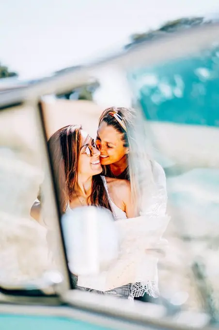 Lesbian couple doing a road trip, kissing and embracing in nature