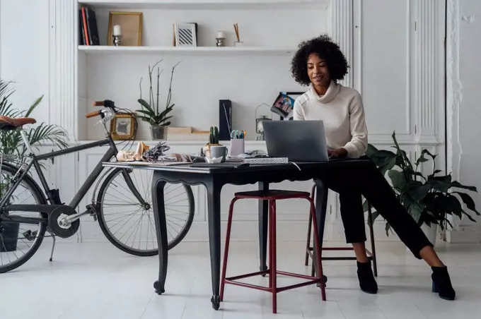 Mid adult woman working in her home office, using laptop