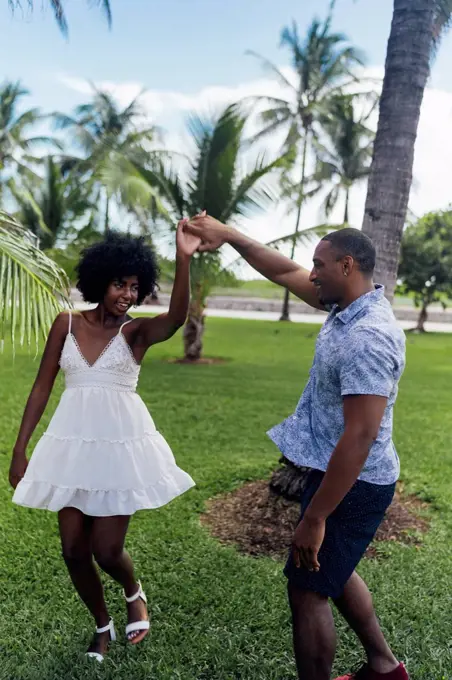 USA, Florida, Miami Beach, happy young couple dancing in a park in summer