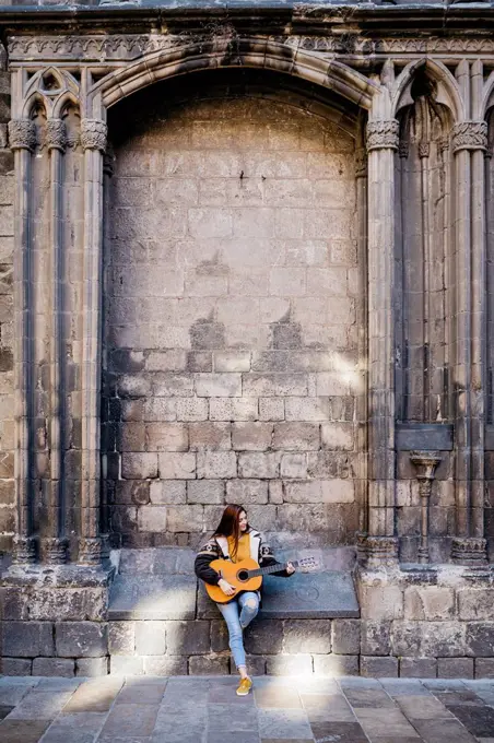 Red-haired woman playing the guitar in the city