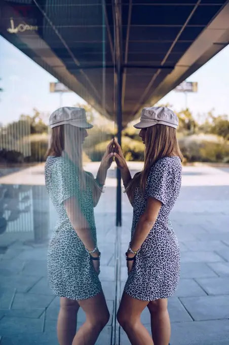 Attractive young woman in leopard print dress reflected in windowpane