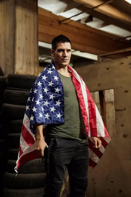 Portrait of man wearing American flag holding a gun