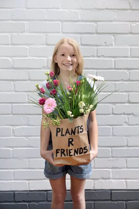 Portrait of smiling girl with paper bag of flowers