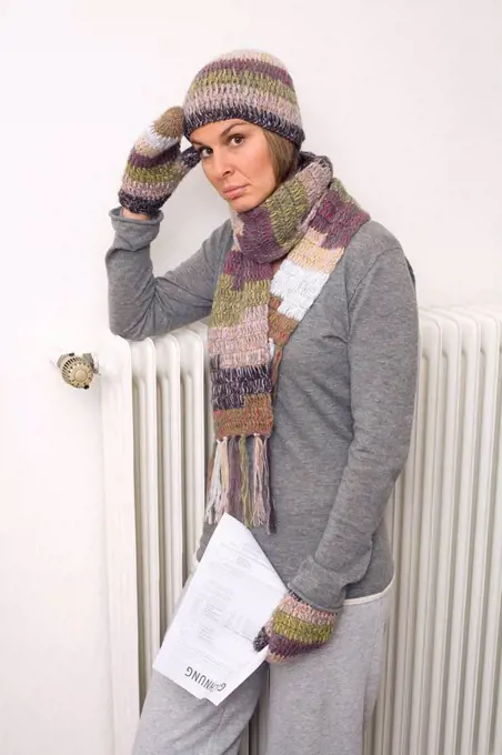 Woman holding utility bill, wearing scarf and cap