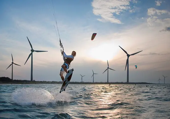 Croatia, Zadar, Kitesurfer jumping in front of wind turbine