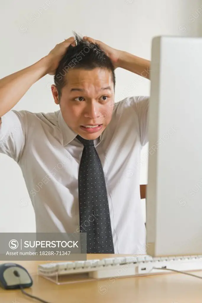 Businessman Pulling his Hair in front of Desktop Computer