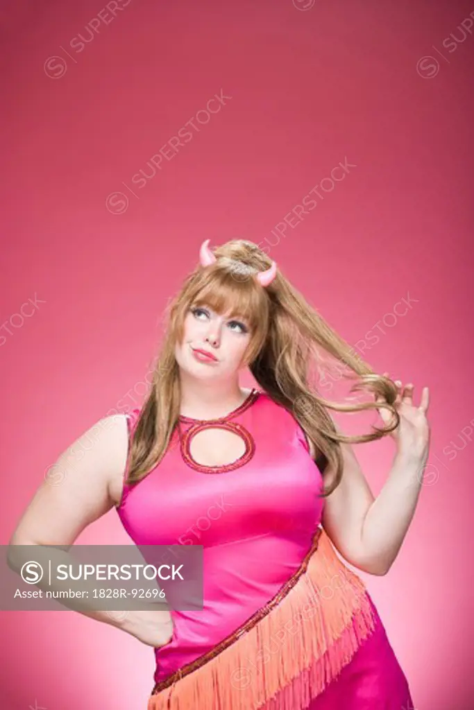 Portrait of woman dressed as a devil, with devil horns having fun and goofing around.