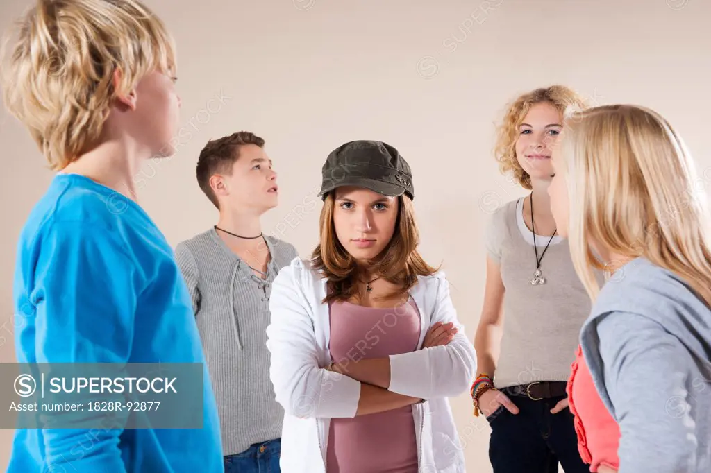 Portrait of Teenage Girl wearing Baseball Hat Looking at Camera, Standing in the Middle of Group of Teenage Boys and Grils, Studio Shot on White Background