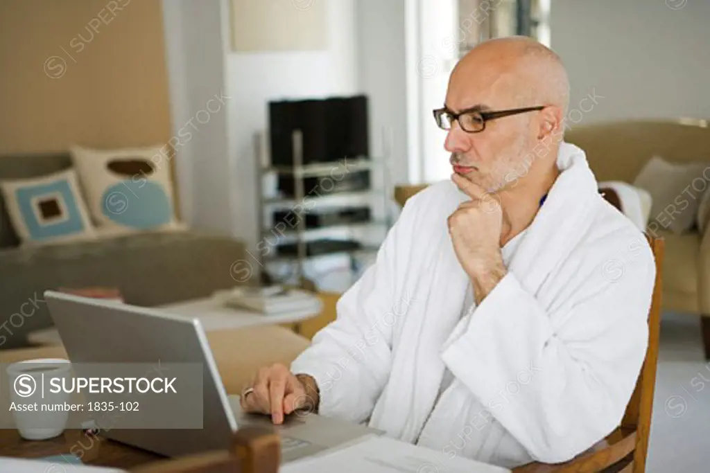 Mature man sitting at a table and working on a laptop