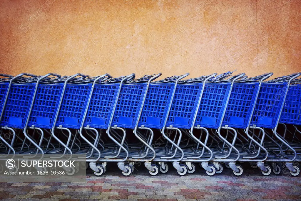 Line of Blue Shopping Carts Against Colorful Wall