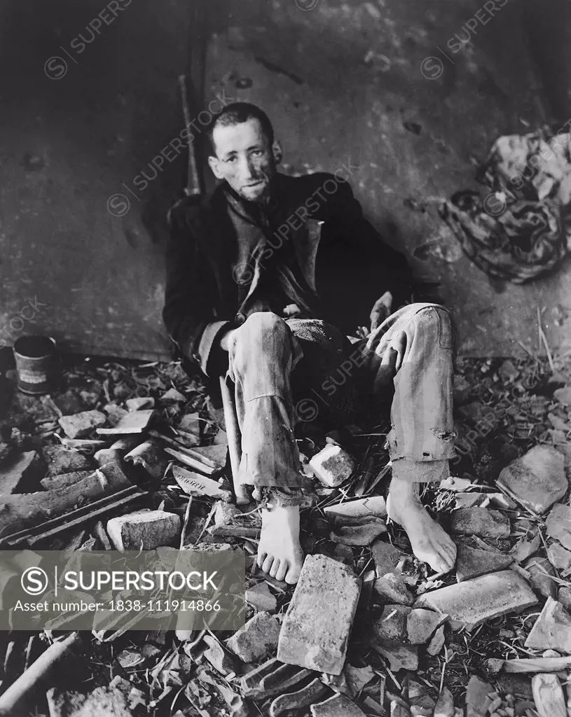 French Prisoner sitting in Rubble waiting for Ambulance to take him to Hospital at German Slave Labor Camp at time of Liberation by U.S. Army, Nordhausen, Germany, photograph by Roberts for U.S. Army Signal Corps, April 1945