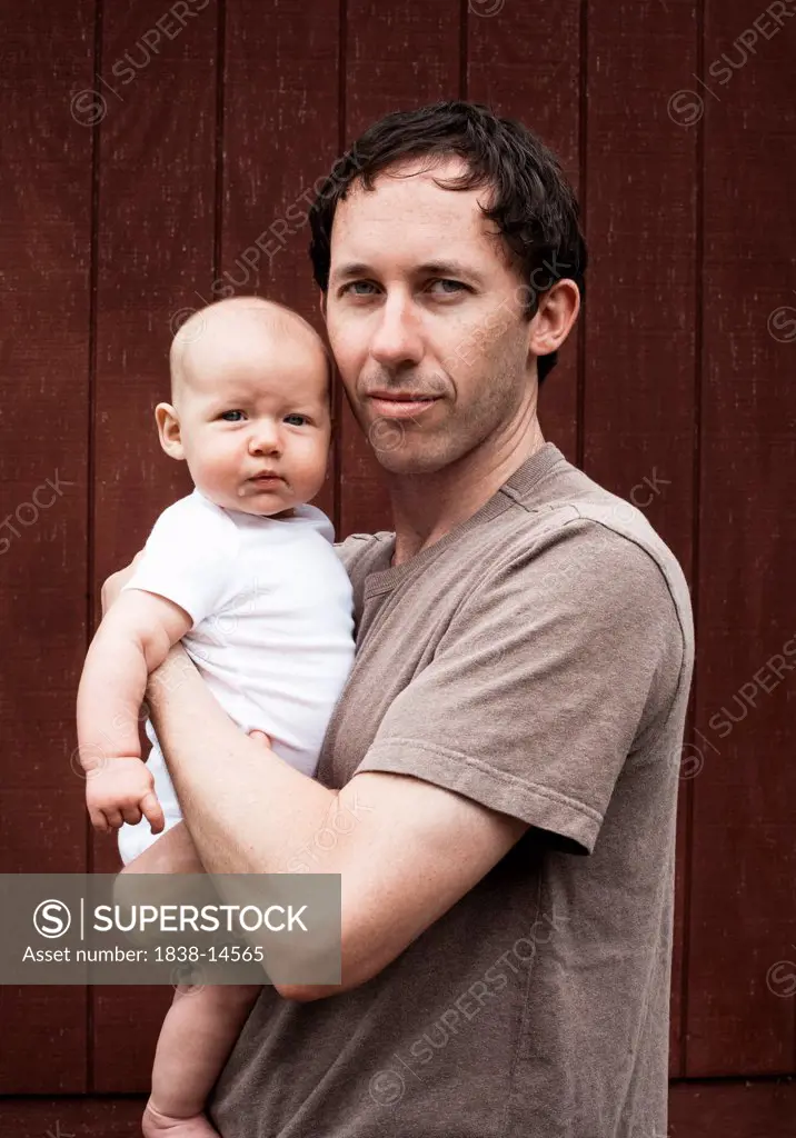 Dad in T-Shirt Holding Baby in Arms