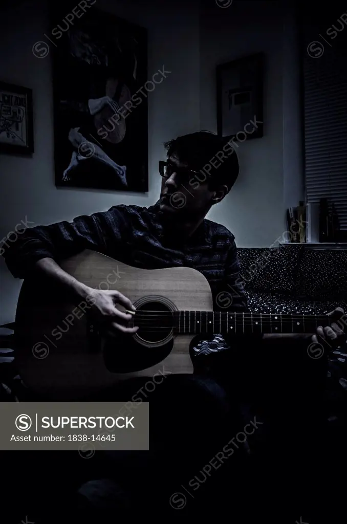 Young Man Playing Acoustic Guitar with Picasso's Blue Period Old Guitarist in Background