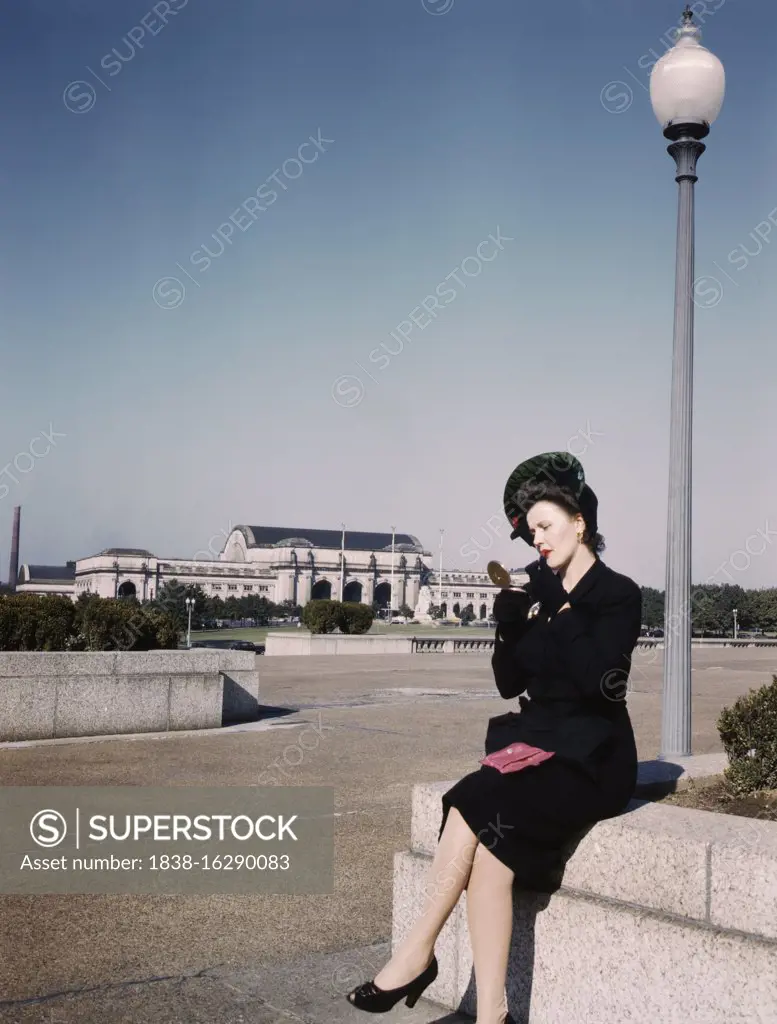 Woman putting on Lipstick in Park with Union Station in Background, Washington, D.C., USA, U.S. Office of War Information, 1943