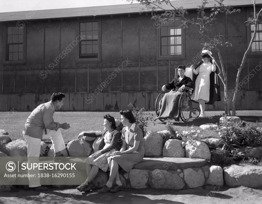 Nurse Aiko Hamaguchi with patient Tom Kano, Young Man talking to Young Women seated on Stone Bench in foreground, Relocation Center, Manzanar, California, USA, Ansel Adams, Manzanar War Relocation Center photographs, 1943