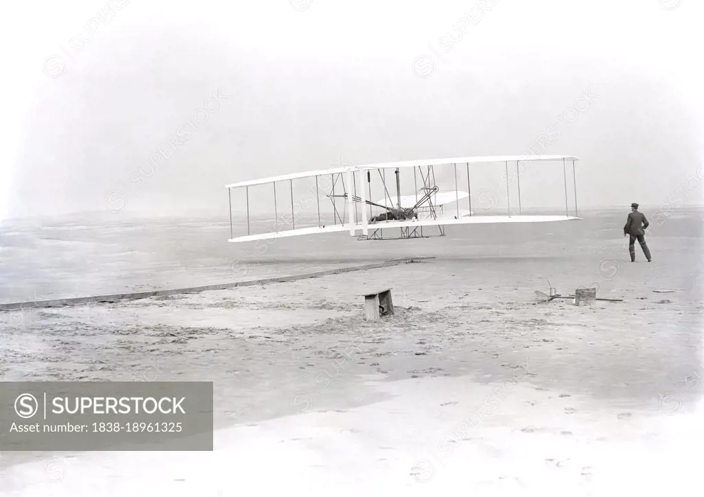 Wilbur Wright lying on machine, Orville Wright running alongside to balance machine, during first powered, controlled, sustained flight, Kitty Hawk, North Carolina, USA, Wilber Wright, Orville Wright, December 17, 1903