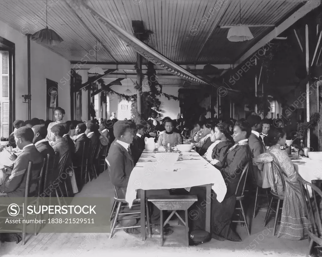 Male and Female Students Sitting at Tables in Dining Hall Decorated for the Holidays, Tuskegee Institute, Tuskegee, Alabama, USA, by Frances Benjamin Johnson, 1902