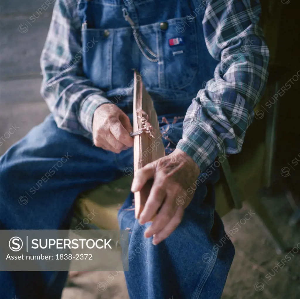 Old Man Sitting, Whittling Wood 