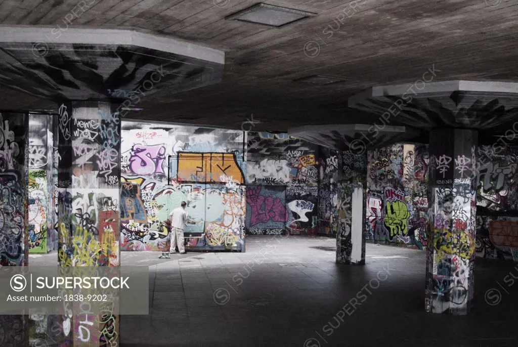 Graffiti Artist Inside Empty Warehouse With Graffiti-Covered Walls