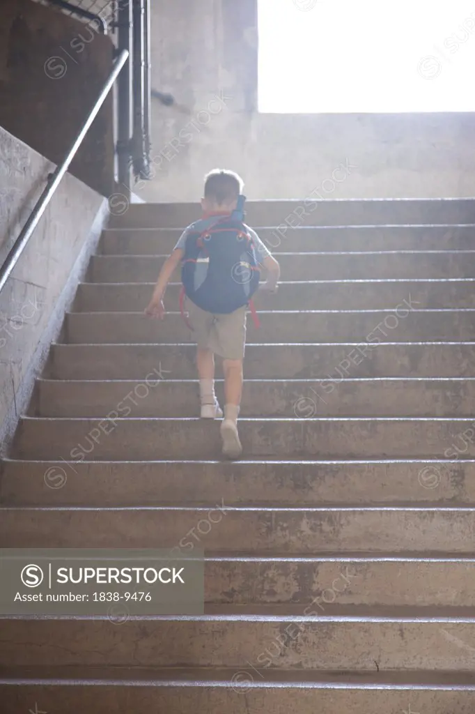 Young Boy with Backpack Walking Up Stairs  