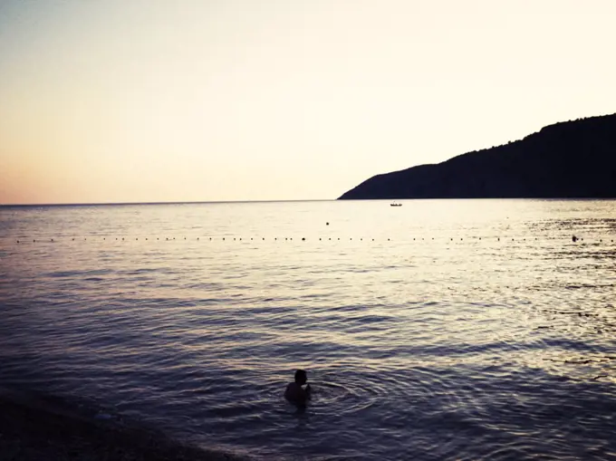 Lone Person Swimming in Calm Sea at Sunset, Croatia