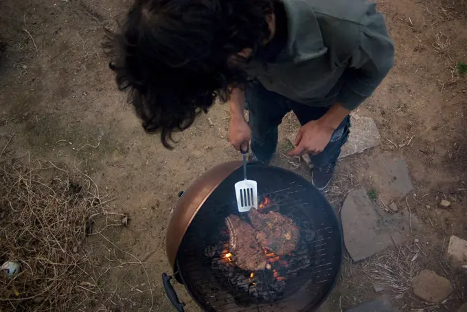 Man Grilling Steaks in Urban Backyard,  High Angle View