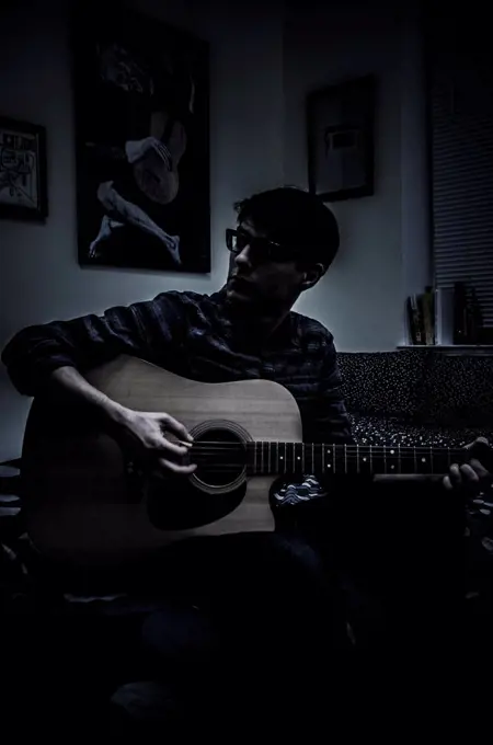 Young Man Playing Acoustic Guitar with Picasso's Blue Period Old Guitarist in Background