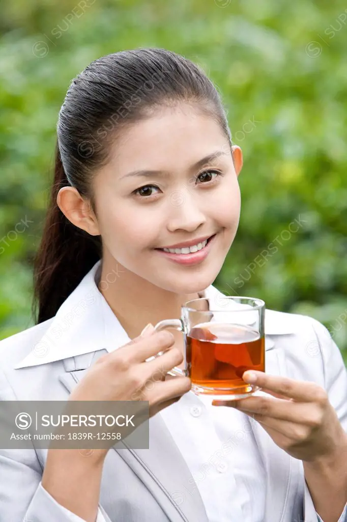 Young Businesswoman in Tea Field with Freshly Brewed Tea