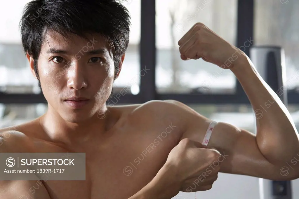 Young Man Measuring Muscles At The Gym