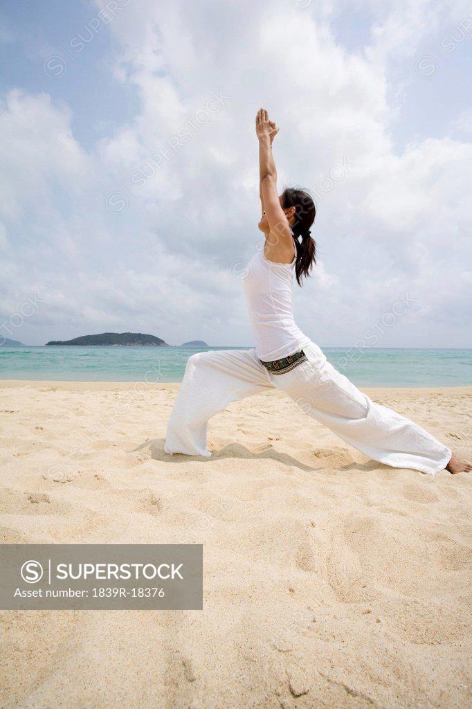 Girl is engaged in yoga on the beach. Young woman in a blue dress