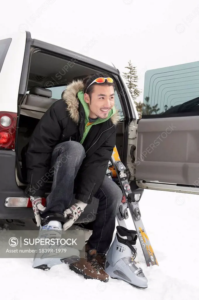 Man Sitting In Car, Putting On Ski Boots