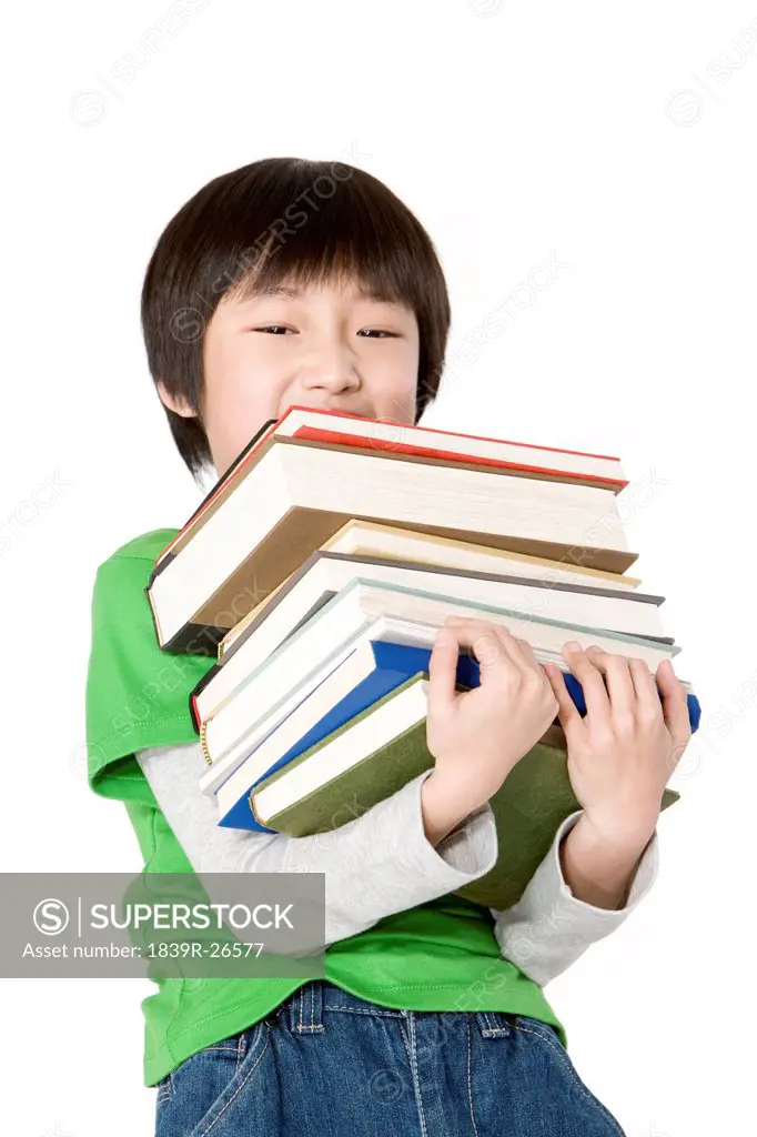 Young boy carrying a large stack of books