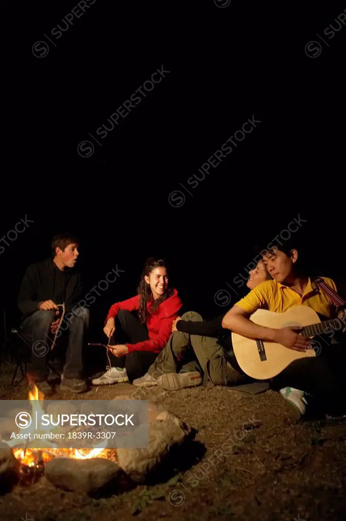 Young People Sitting Around Campfire