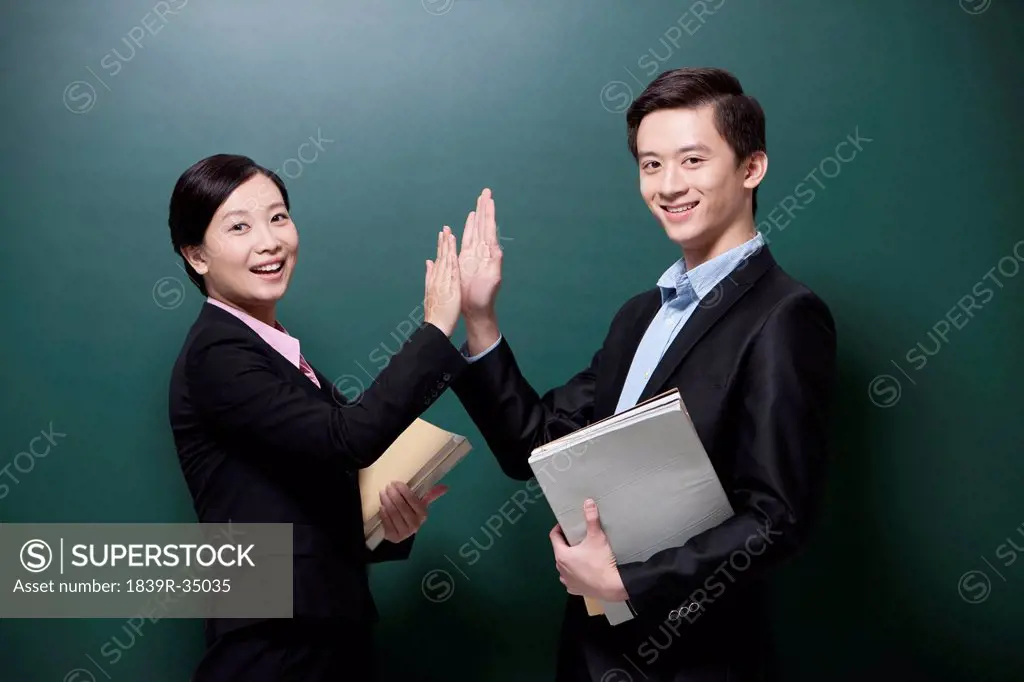 Professional male teacher and female teacher doing high-five