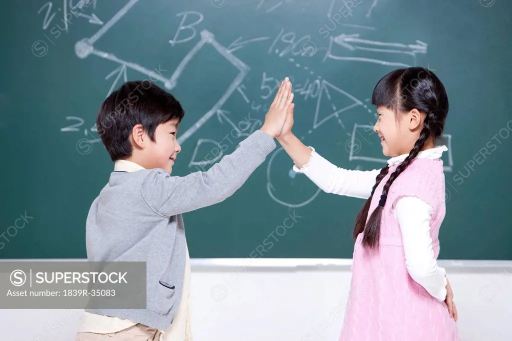 Little boy and little girl doing high-five in classroom