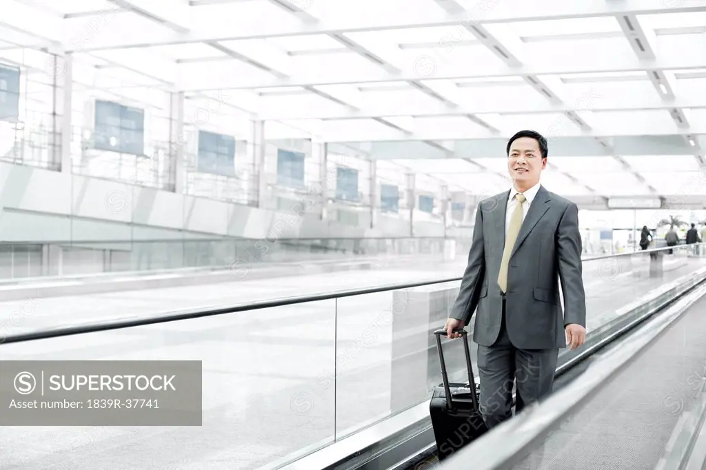 Mature businessman with wheeled luggage on airport escalator