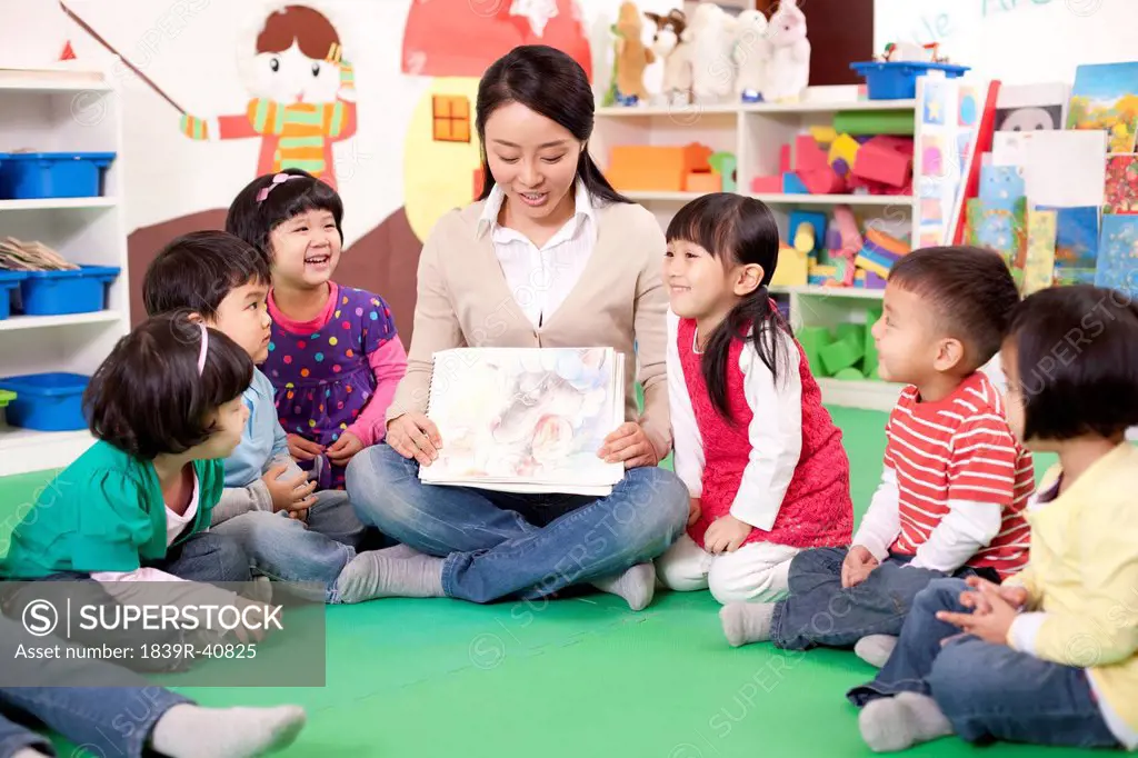 Female teacher showing kindergarten children picture book