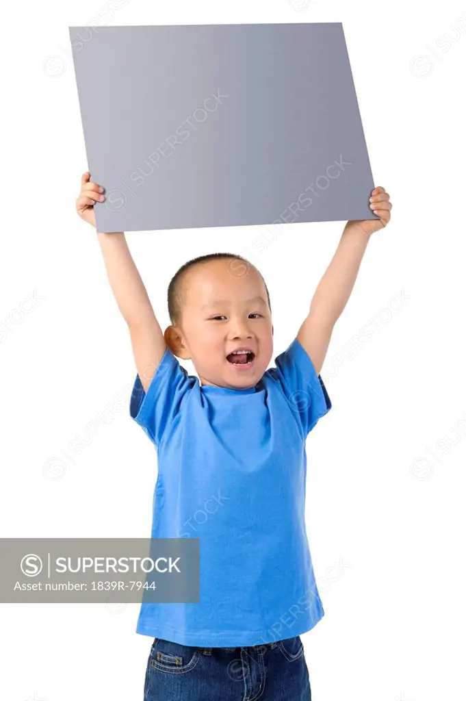 Young boy stands, holding a placard above his head