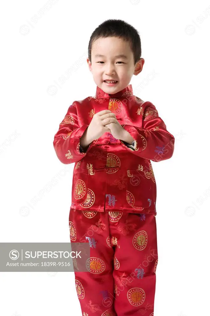 Boy in Chinese traditional clothes doing Chinese New Year greeting