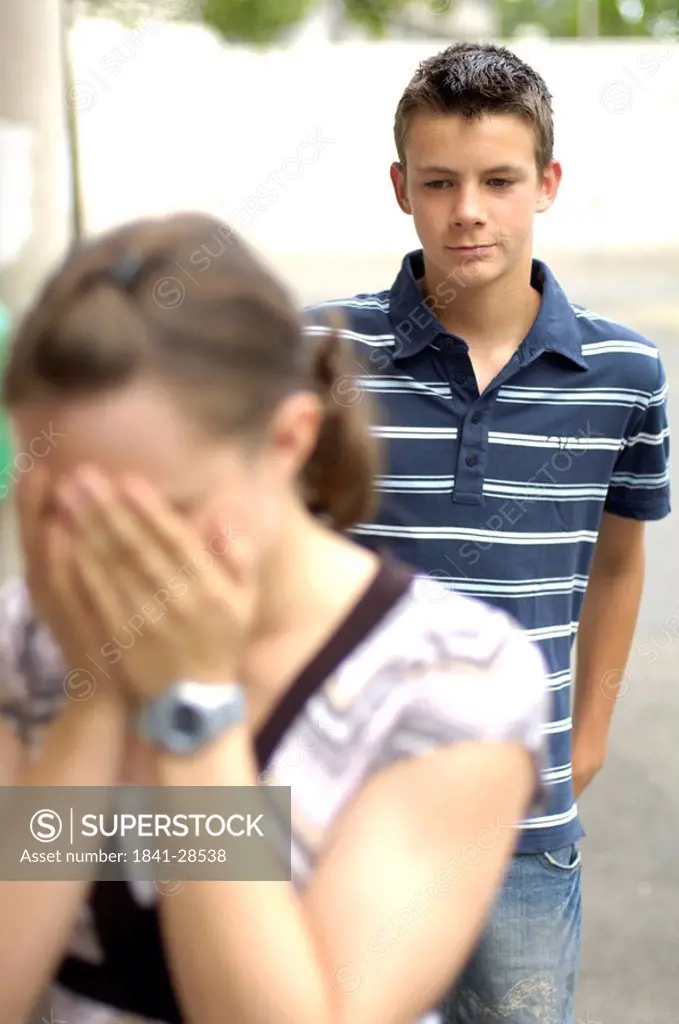 Close_up of teenage girl sobbing with her friend standing in background