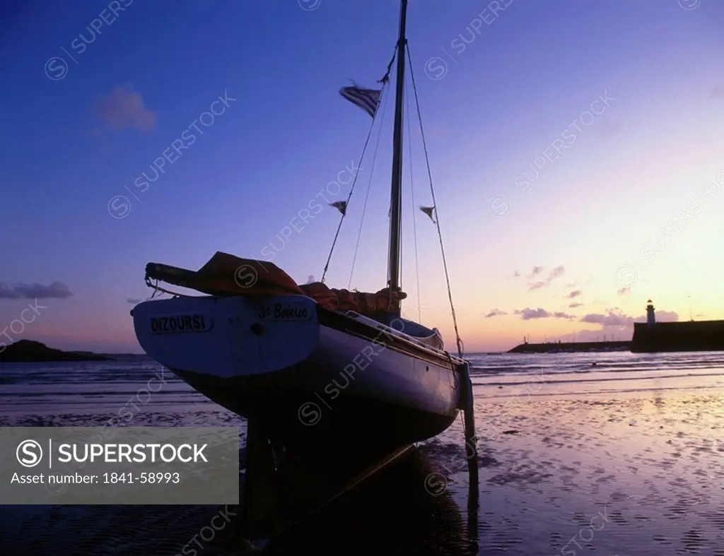 Silhouette of sailboat on beach, Port Erquy, Brittany, France