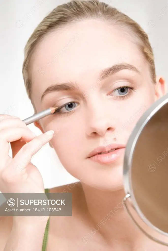 young woman putting on eyeliner