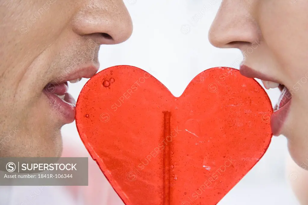 Couple eating heart shaped lollipop