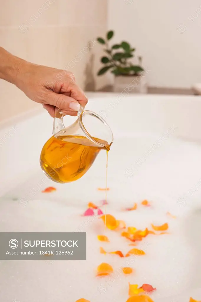 Woman pouring bath oil in bath tube