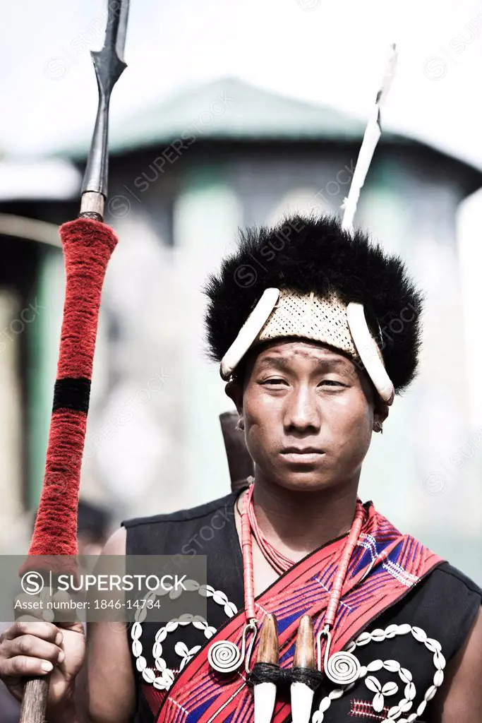 Naga tribesman in traditional outfit holding a spear during the annual Hornbill Festival at Kisama, Kohima, Nagaland, India