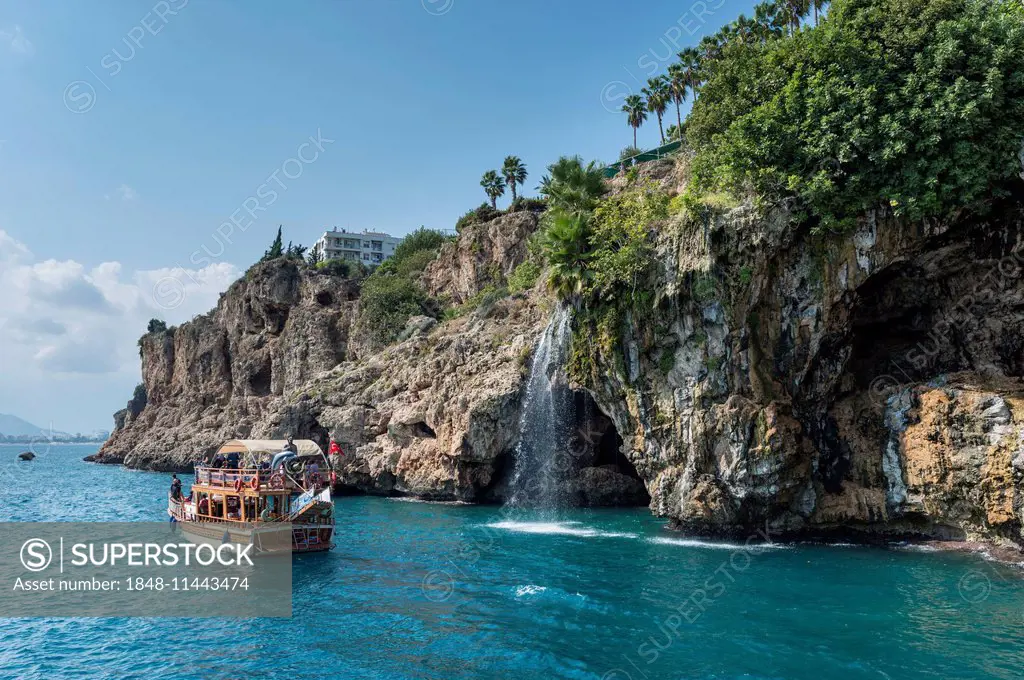 Excursion boat in the Gulf of Antalya, cliffs with waterfall, Yavuz Özcan Park at the top, Antalya, Turkish Adriatic, Turkey